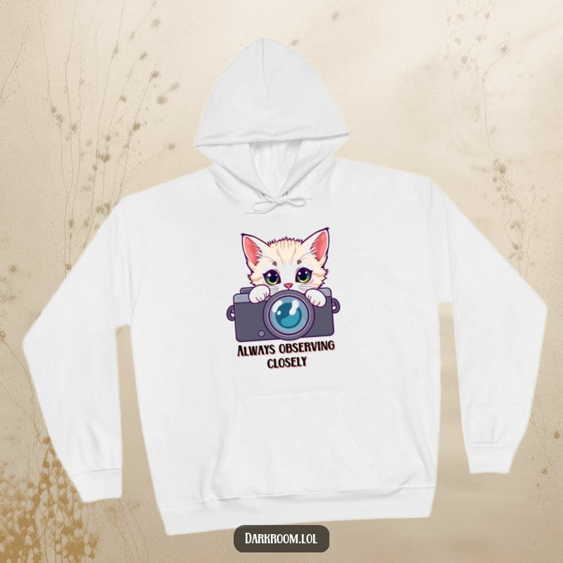 Funny kitten photographer hoodie, peeking through a camera lens with curious eyes, offering warmth and a touch of playful artistic charm.